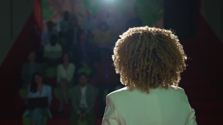 Rear view of the Public speaker giving talk at conference event.